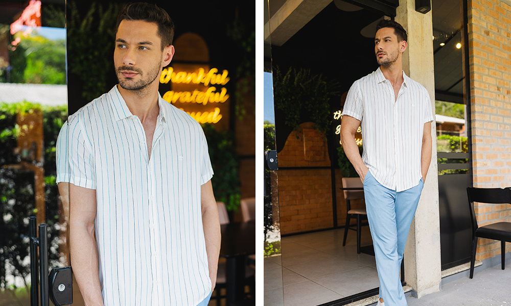 Dois momentos do mesmo homem vestindo uma camisa listrada de fundo claro, com um design leve e casual. À esquerda, ele está à porta de um local iluminado por um neon que transmite um ambiente acolhedor e moderno. À direita, ele aparece em um espaço com paredes de tijolos aparentes, combinando a camisa com uma calça azul clara, criando um visual descontraído, perfeito para encontros sociais em dias ensolarados.